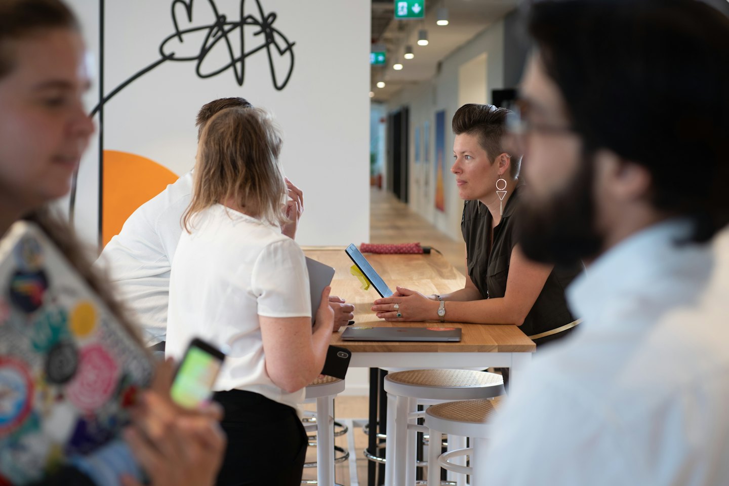 Professionals collaborate around a high wooden table in a modern office.